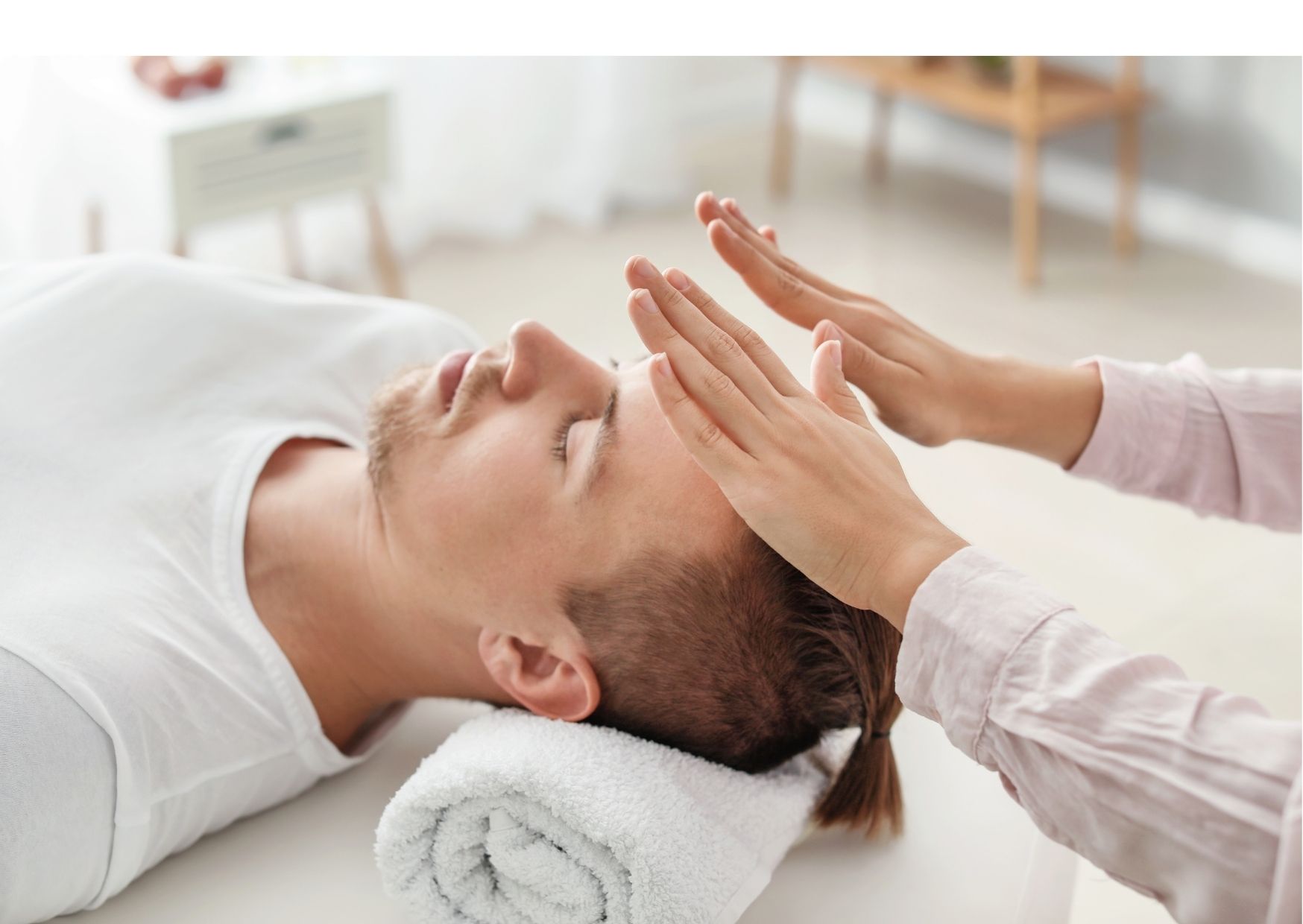 A man receiving Reiki while resting his head on the rolled towel