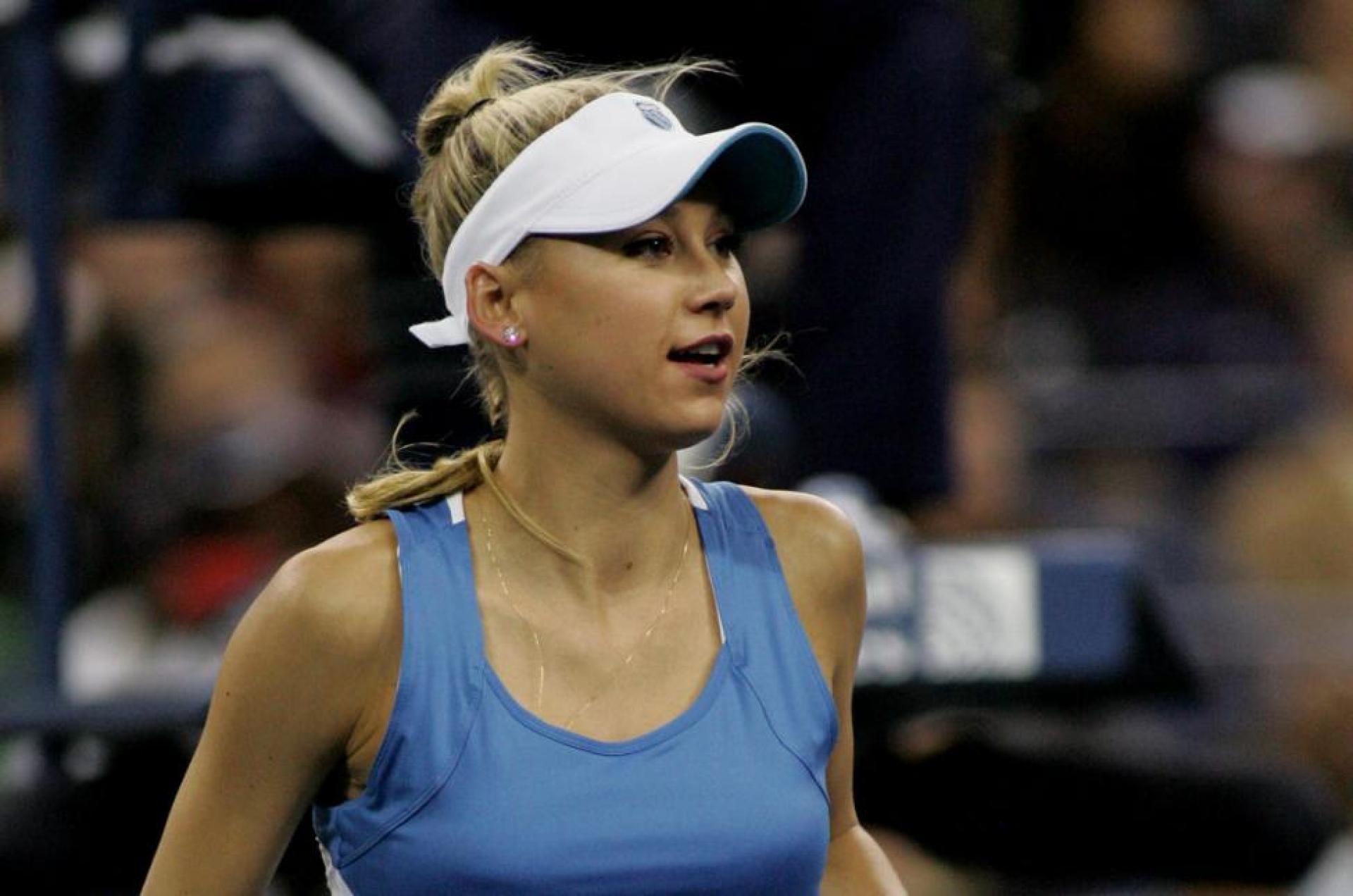 A blonde woman wearing a blue shirt and a white cap