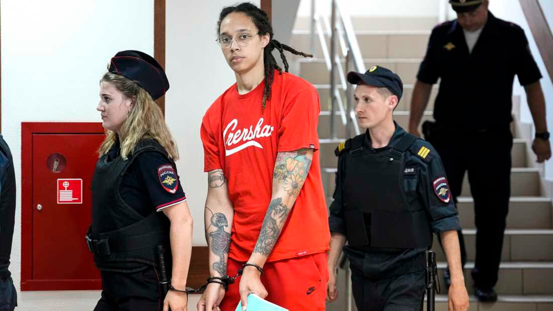 Brittney Griner with handcuffs and escorted by several police 