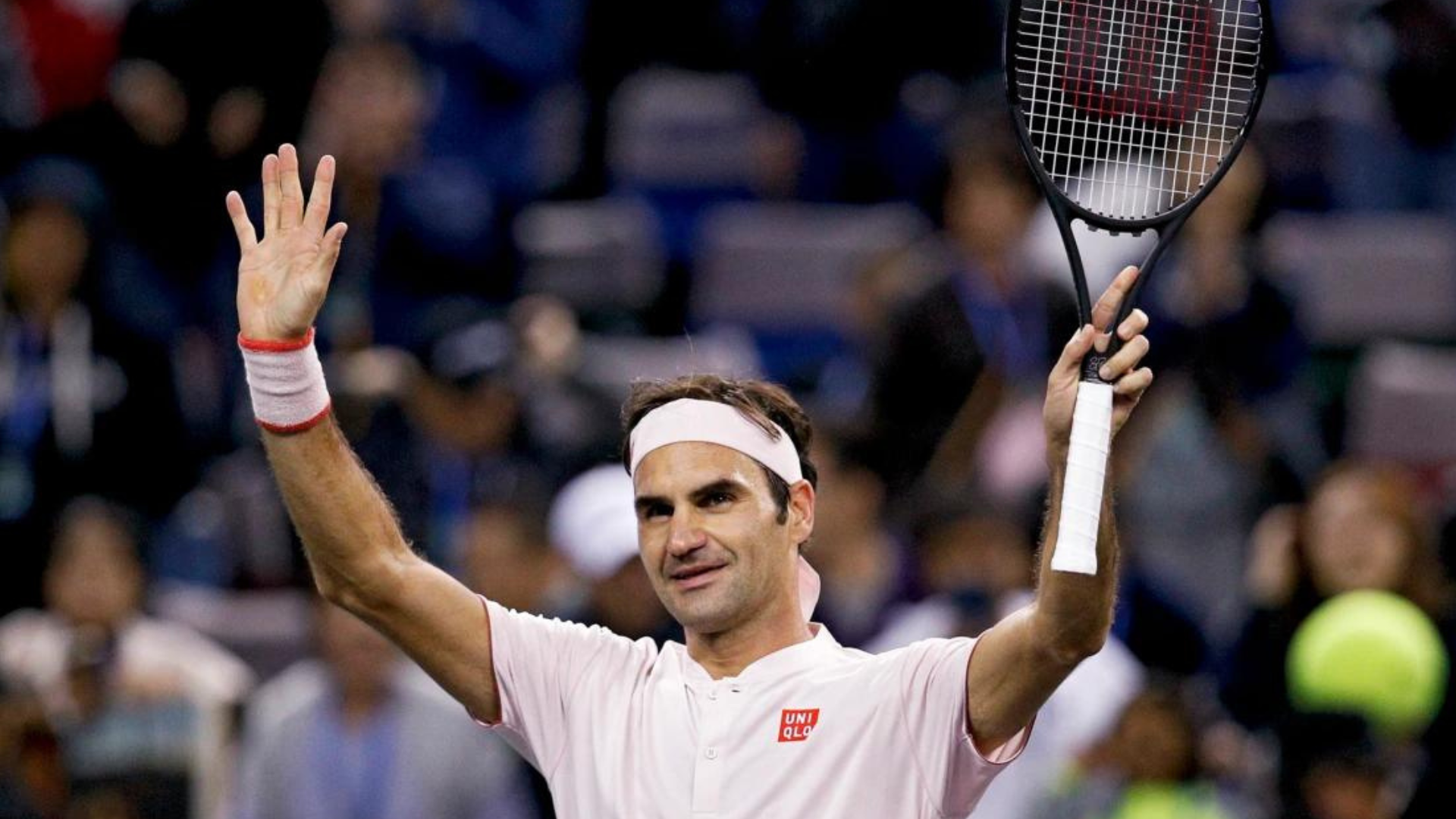 Roger Federer holding a tennis rocket with his hands raised up high