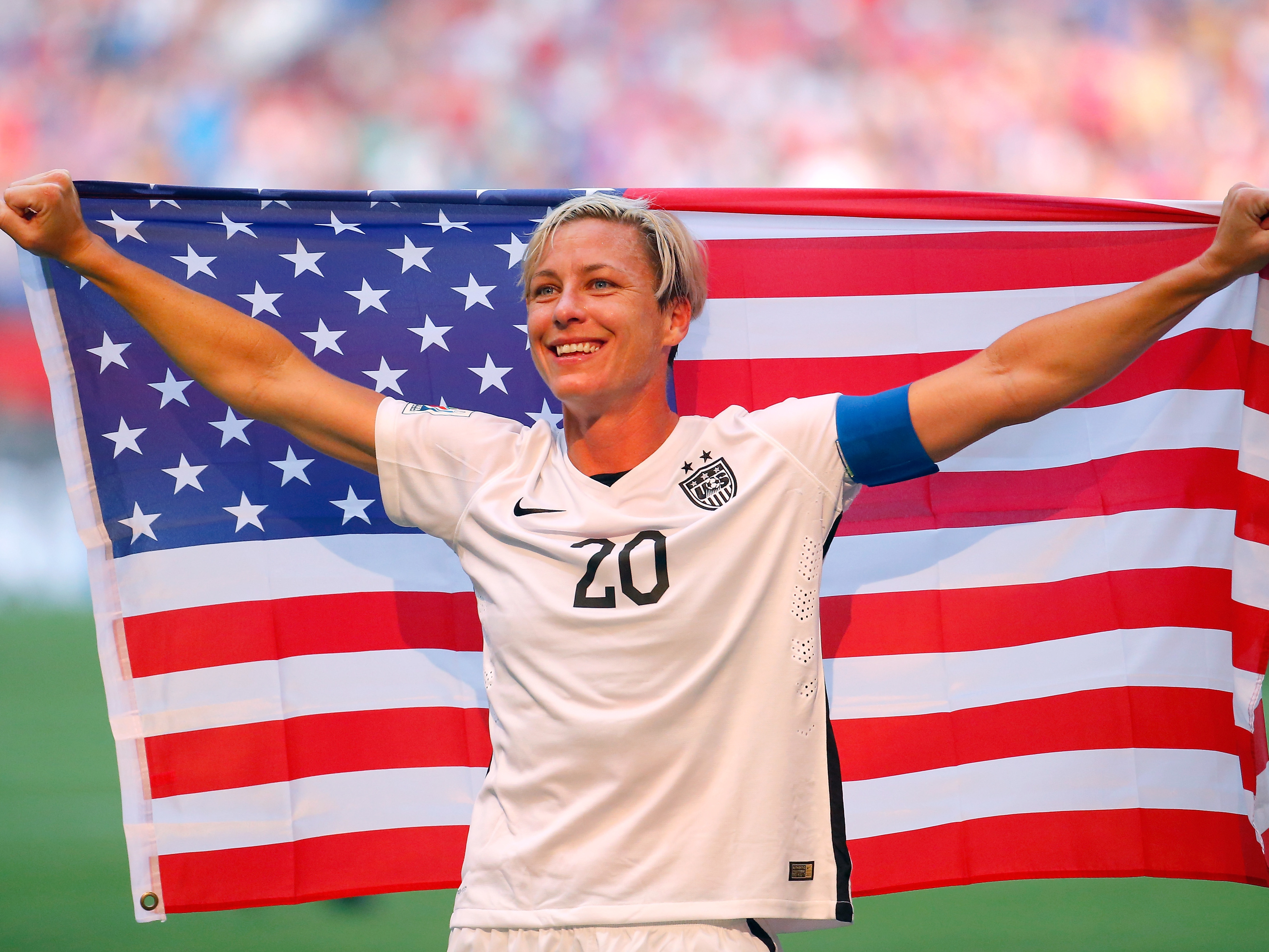 A blonde woman smiling and holding American flag