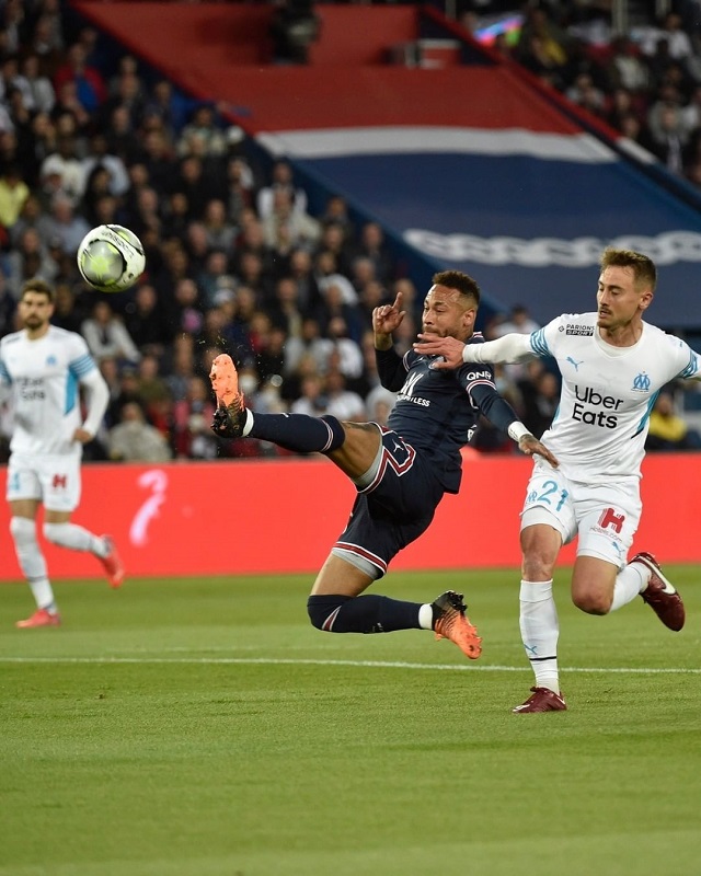 Neymar in mid-air after kicking a ball and being chased by Olympique de Marseille’s Valentin Rongier