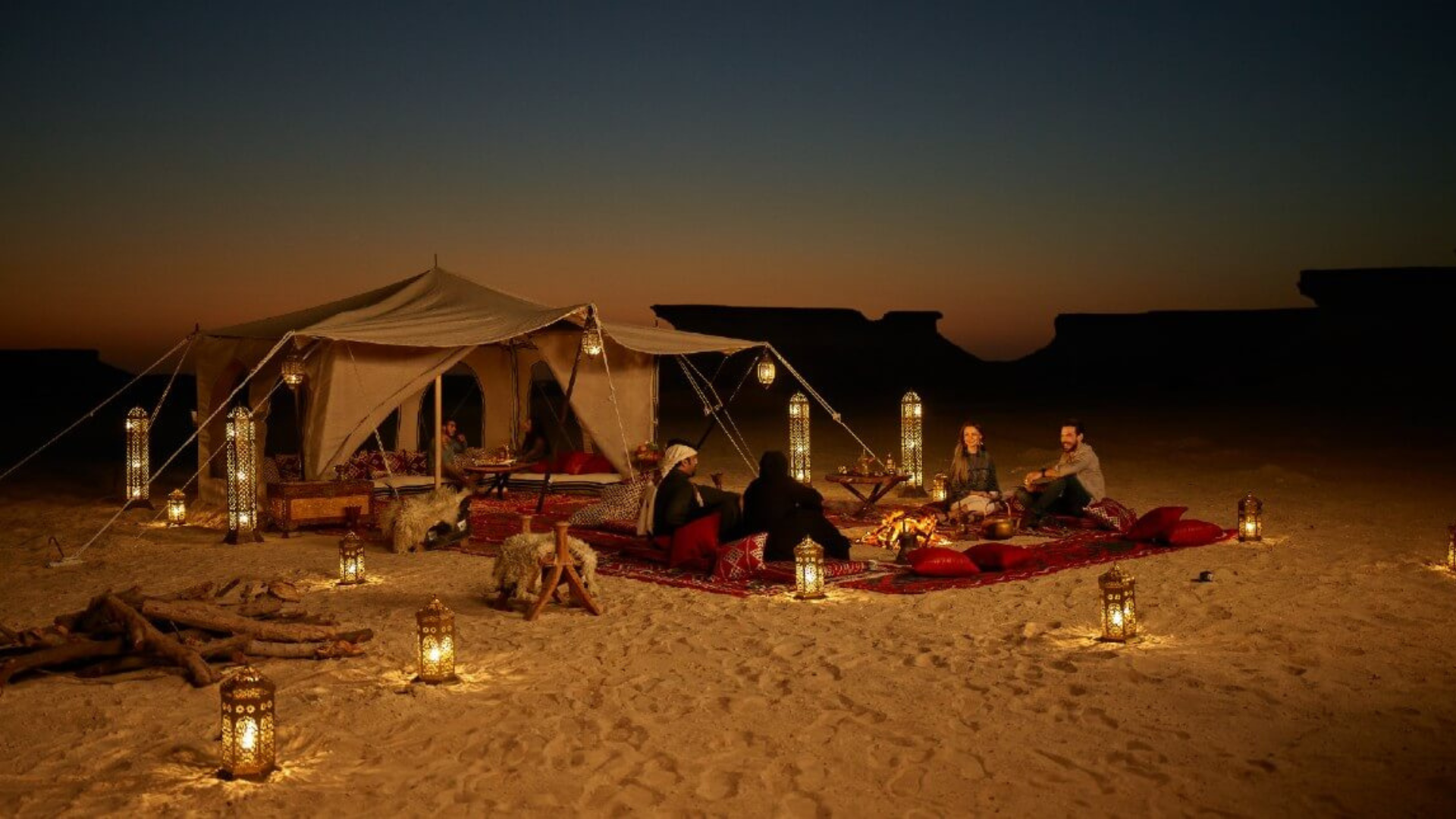 A small tent in the dessert with a group of people
